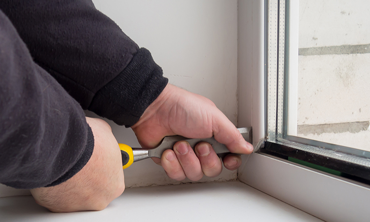 Hand holding screwdriver working on window frame installation